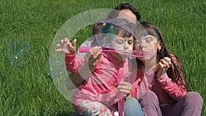 Children with mom are playing with soap bubbles. Happy family on nature in summer. Girl with children in the park on a sunny day p