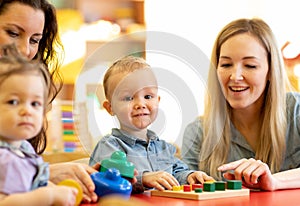 Children with moms play with color wooden puzzle in a montessori classroom