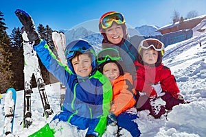 Children and mother, family on ski vacation sit together in snow