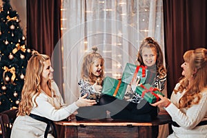 Children with mother and grandmother in their hands holding boxes with gifts in green packaging. Christmas mood. Celebrate the