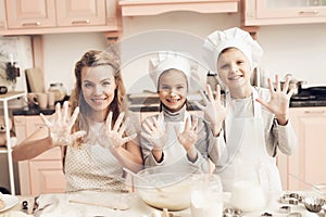 Children with mother in kitchen. Family is showing on camera hands in flour.