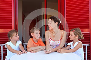 Children and mother sit on verandah round table