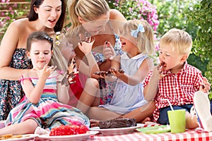 Children And Mothers Eating Cake At Outd
