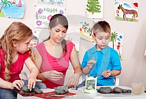 Children mould with teacher from clay.