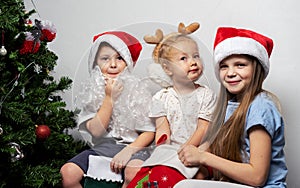 Children near Christmas tree are looking for gifts in Santa`s stocking.