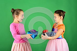 Children open gifts for Christmas. Sisters with wrapped gift boxes