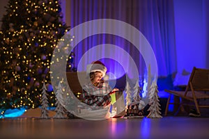 Children opening presents on Xmas eve. Lighting in magic Christmas night at cozy home. Cute child on Christmas night at