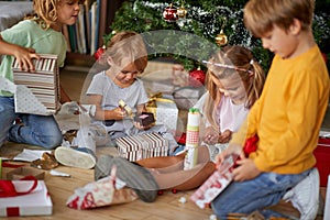 Children opening Xmas presents. Kids under Christmas tree with gift boxes