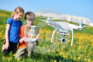 children operating of flying drone at field