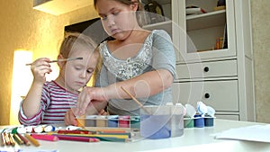 Children paint on paper with colors and brushes