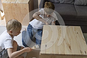 Children paint wooden pedestal. Two brothers help make the table. Joinery. Carpentry workshop