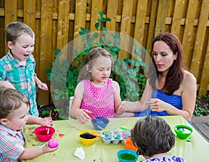 Children Painting Easter Eggs Outside with Mom