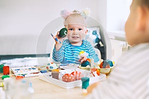 Children painting eggs. Family preparing for Easter