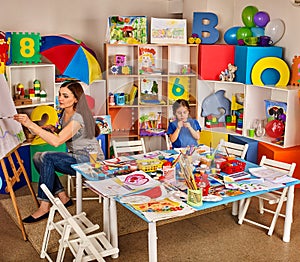 Children painting finger on easel. Group of kids with teacher.