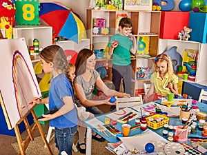 Children painting finger on easel. Group of kids with teacher.