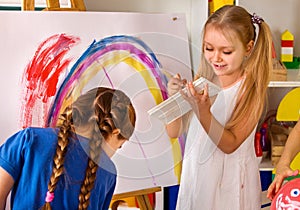 Children painting finger on easel. Group of kids with teacher.