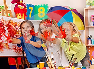 Children painting finger on easel. Small students in art school class.