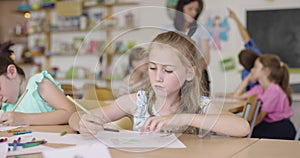 Children painting in playroom. Two little girls drawing on paper at the table in classroom.