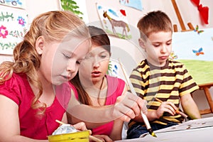 Children painting with teacher.