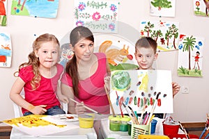 Children painting with teacher in art class.