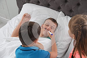 Children painting their father`s face while he sleeping