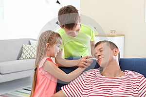 Children painting their father`s face while he sleeping