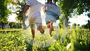 children in the park. bare feet close up a children running. happy family kid dream concept. children hold hands run