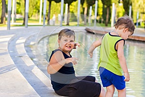 Children in the park dip their feet in the fountain they are very happy. Have fun and rejoice on a summer day at the fountain