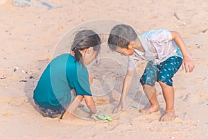 Children picking up Plastic bottle and gabbage that they found on the beach for enviromental clean up concept