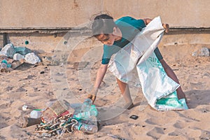 Children picking up Plastic bottle and gabbage that they found on the beach for enviromental clean up concept