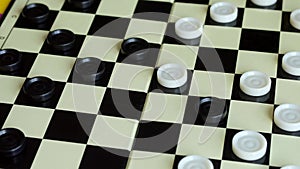 Children play checkers on a colorful table. Boy and girl compete in board games.