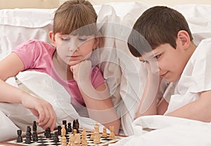 Children play chess in a bed