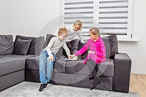 Children play chess sitting on sofa in room. Little sister toddler having fun. Concept of family