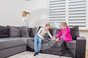 Children play chess sitting on sofa in room. Little sister toddler having fun. Concept of family