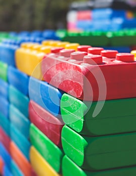 Children play colorful big toy blocks in kindergarten day care center playground, kids playing with various plastic mega