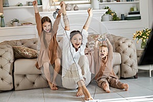 Children play on the console with their mother. The joy of passing a computer game. Mom son and daughter battle on the console.