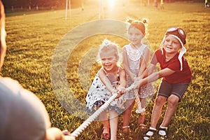 Children play with dad in the park. They pull the rope and have fun laying on a sunny day