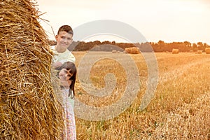 Children play in the field behind a haystack and pose for the camera. Children in nature. Lifestyle