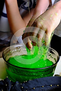 Children play with a green witchcraft potion, table is covered with a black cloth, pumpkins lie, animal skulls, candles are