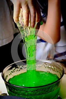 Children play with a green witchcraft potion, table is covered with a black cloth, pumpkins lie, animal skulls, candles are