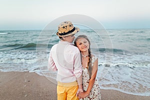 Children play and have fun on the beach.Girl with boy hold hands. Retro style