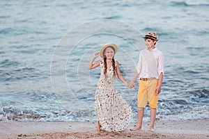 Children play and have fun on the beach. The girl and the boy stand and hold hands