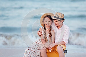 Children play and have fun on the beach. The girl and the guy run away from the wavesThe girl and the boy are sitting on a yellow