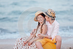 Children play and have fun on the beach. The girl and the guy run away from the wavesThe girl and the boy are sitting on a yellow