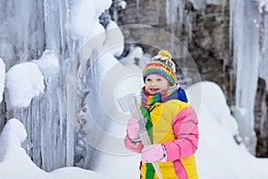 Children play with icicle in snow. Kids winter fun