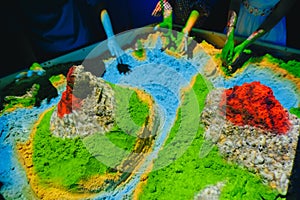 Children play with kinetic sand. Concept simulator of earth, volcanoes, relief and soil surface