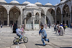 Children play in the magnificent courtyard of the Blue Mosque in the Sultanahmet district of Istanbul in Turkey.