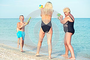 Children play with my mother and grandmother with water pistols on the beach.Summer time