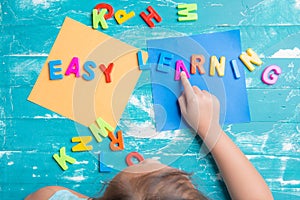 Children play plastic letters to combinations word `Easy Learning`