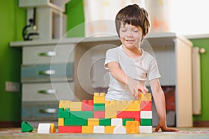 Children play with a toy designer on the floor of the children's room. Boy playing with colorful blocks